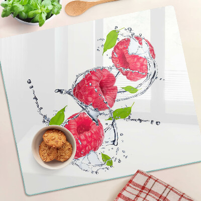 Schneidebrett glas Himbeeren im Wasser mit Blättern