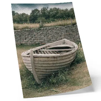 Kunstdruck auf Leinwand verlassenes Boot bei einer Mauer inmitten von Gras und Natur