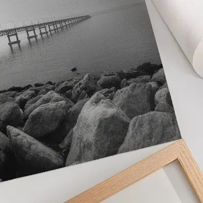 Poster friedliche Landschaft mit Brücke am felsigen Strand unter grauem Himmel