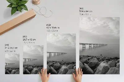Poster friedliche Landschaft mit Brücke am felsigen Strand unter grauem Himmel