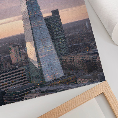 Wandposter Ein Wolkenkratzer im Sonnenuntergang, der einen Kontrast zur Stadt bildet.