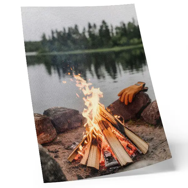 Wandposter mit Motiv von einem Lagerfeuer am See, Waldsteinen und einer naturnahen Erholungslandschaft