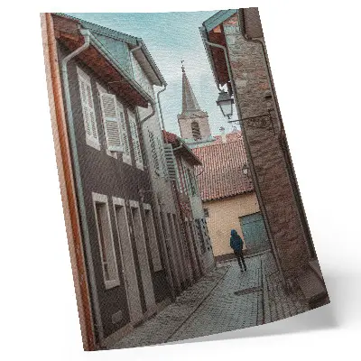 Poster enge Straße mit Mietshäusern, einem Turm und einer Person in einem blauen Mantel