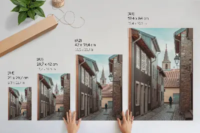 Poster enge Straße mit Mietshäusern, einem Turm und einer Person in einem blauen Mantel