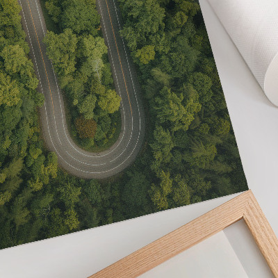 Wandposter Eine schmale, gewundene Straße durch den grünen Wald