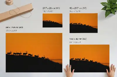 Kunstdruck Poster mit Silhouetten von Hirschen auf einem Hügel vor orangefarbenem Hintergrund