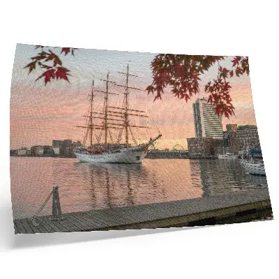 Poster Segelschiff im Sonnenuntergang mit friedlichem Stadtpanorama