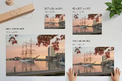 Poster Segelschiff im Sonnenuntergang mit friedlichem Stadtpanorama